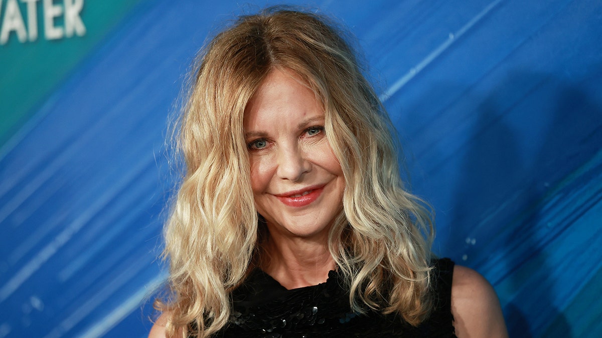 Meg Ryan in a black dress soft smiles on the carpet