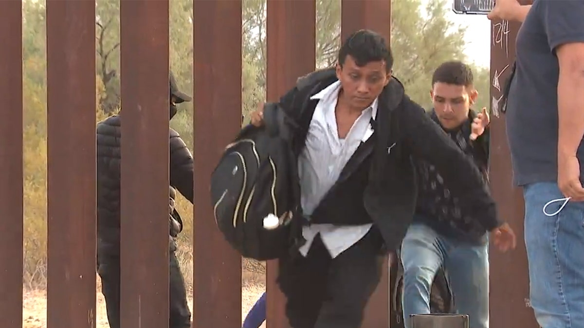 migrants through border wall 