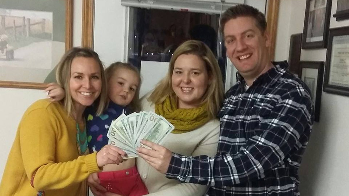 Jeremy Morris holds fan of 0 bills with wife, daughter and another woman