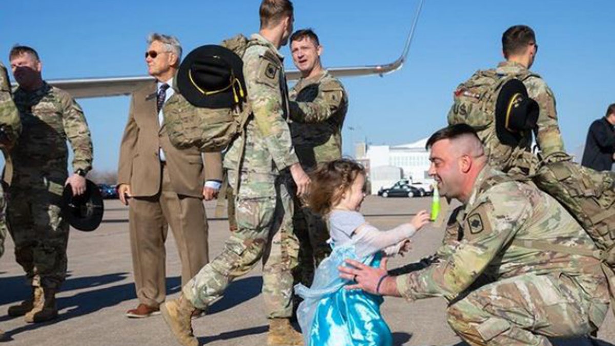 Girl embraces her soldier father