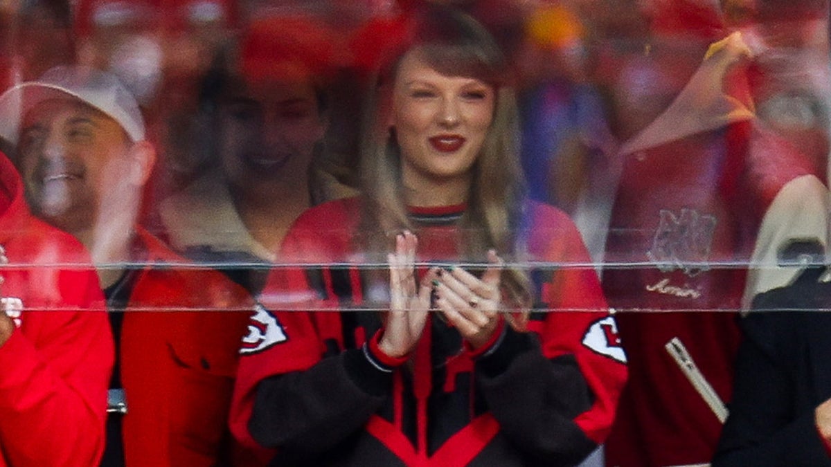 Taylor Swift claps in red apparel while attending a Chiefs game