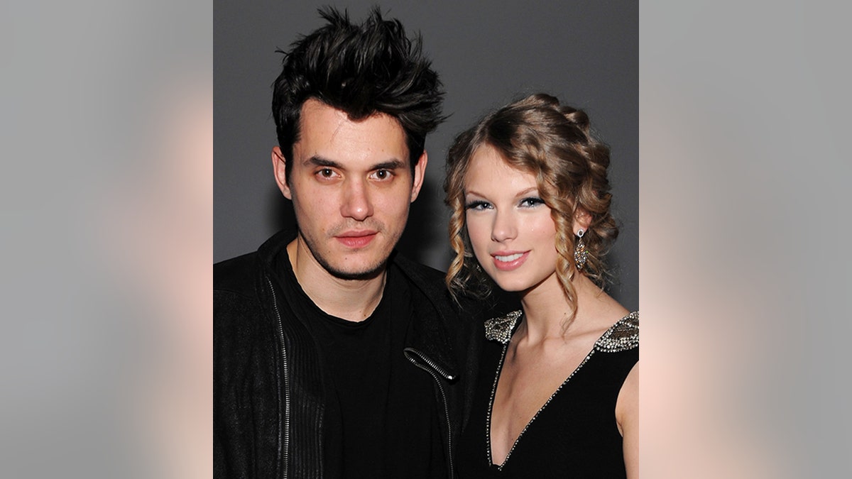 John Mayer in black poses next to Taylor Swift in a black dress at an event in New York City