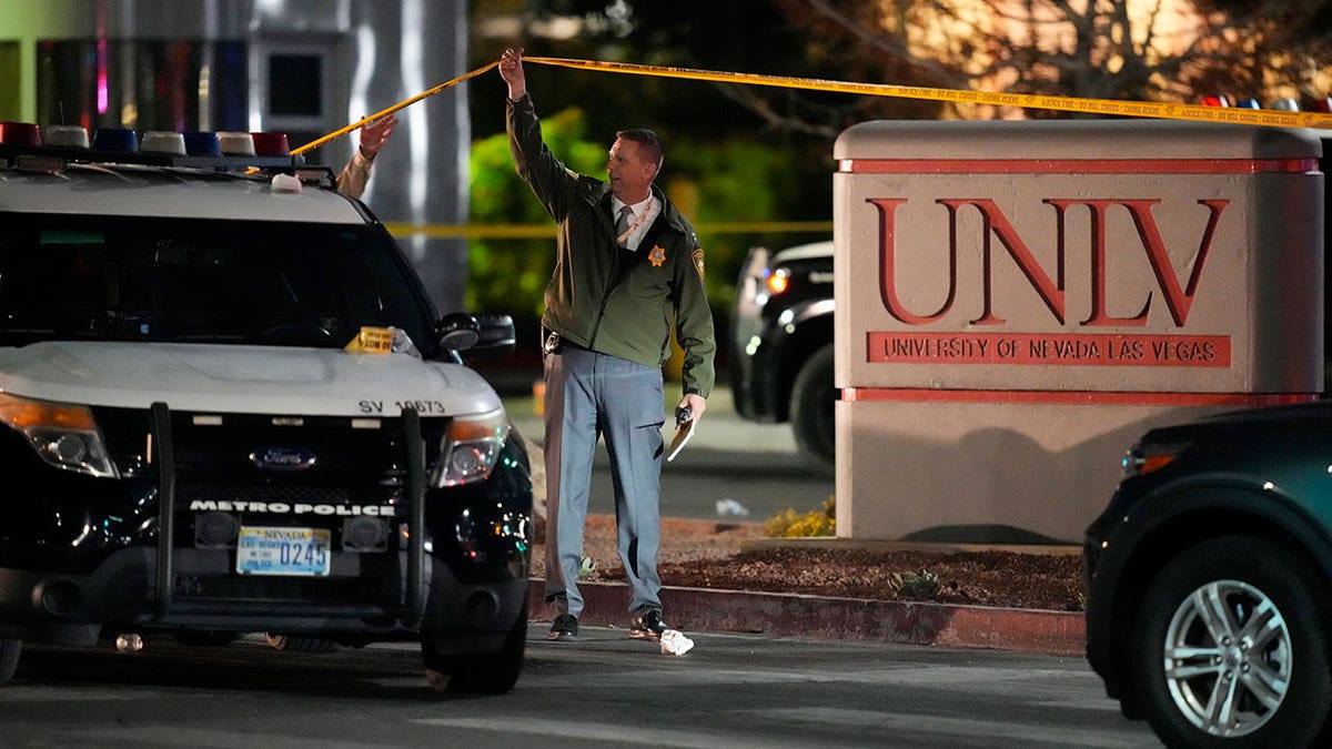 A police officer holds up crime scene tape at the University of Nevada, Las Vegas