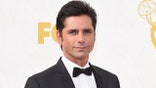 John Stamos in 2015 wearing a bowtie and black coat.