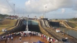A ship passing through the Panama Canal, as people watch