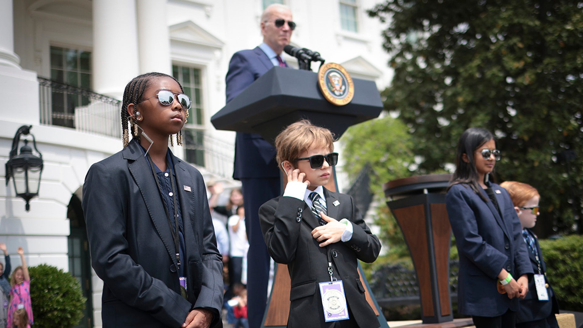 oe Biden speaks while children dressed as Secret Service agents "guard" the stage on Take Your Child To Work Day