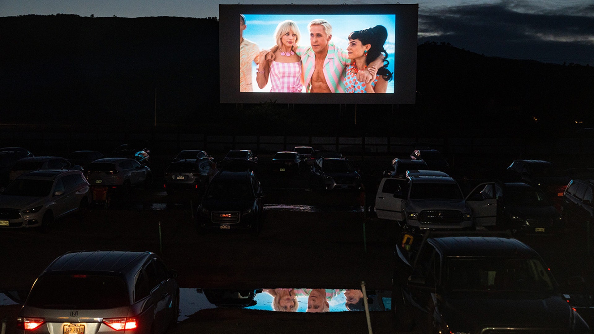 A preview for "Barbie" plays on a screen at a drive-in theater