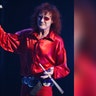 Colin Burgess with long red hair, red glasses, in a red outfit