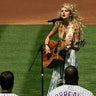 Taylor Swift sings the national anthem before a baseball game.