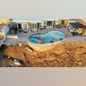 An aerial view of a remaining pool at the edge of a hillside landslide in California
