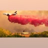 Residents stand on their roof as a DC-10 Air Tanker drops fire retardant