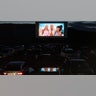 A preview for "Barbie" plays on a screen at a drive-in theater