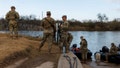 Texas National Guard soldiers wait nearby the boat ramp where law enforcement enter the Rio Grande at Shelby Park on January 26, 2024 in Eagle Pass, Texas.