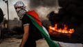 A Palestinian dons a Palestinian flag during while protesting Israeli occupation in the West Bank, as protesters are met with tear gas, flashbang and live fire from Israeli forces, in Beit El area of Ramallah, Israel, Friday, Oct. 13, 2023. Tensions are rising all across Israel and Palestinian Territories as Israel&Otilde;s military prepares for a wide scale incursion into Gaza in the country's south.