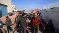 Palestinians carry a a body of a person killed in the Israeli bombardment at a building of an UNRWA vocational training center which displaced people use as a shelter in Khan Younis, southern Gaza Strip, on Jan. 24, 2024.