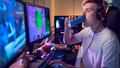 Teenage Boy Drinking Caffeine Energy Drink Gaming At Home Using Dual Computer Screens At Night