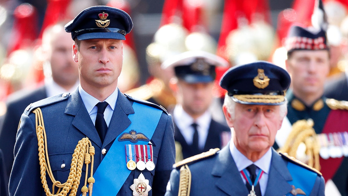 Prince William looking serious in uniform next to King Charles also in uniform