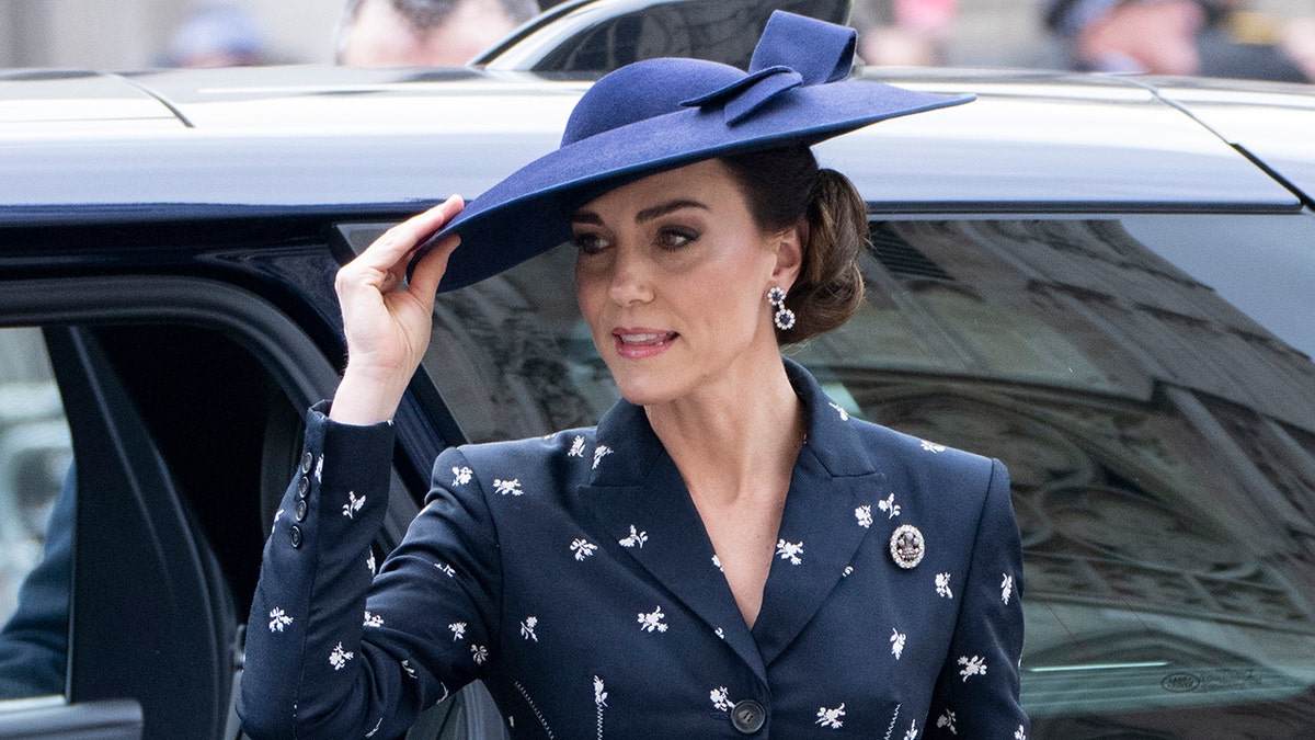 Kate Middleton wearing a dark blue suit dress with a matching hat