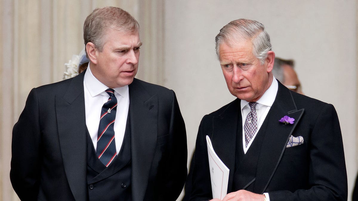 Prince Andrew looking at King Charles as they both wear matching dark suits