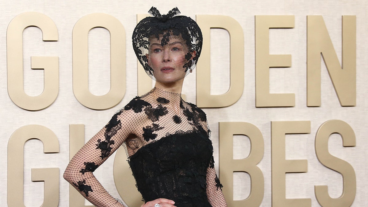 Rosamund PIke wearing veil and posing with hand on hip