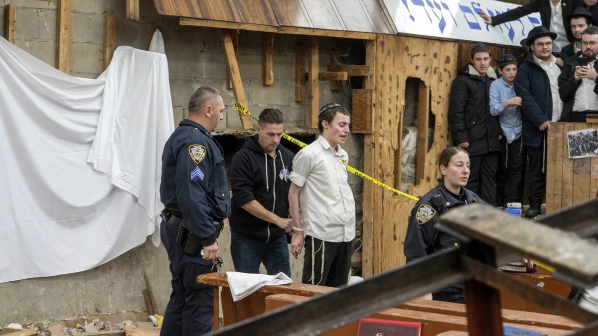 NYPD officers arrest a students after he was removed from a breach in the wall of the synagogue that led to a tunnel dug by students.