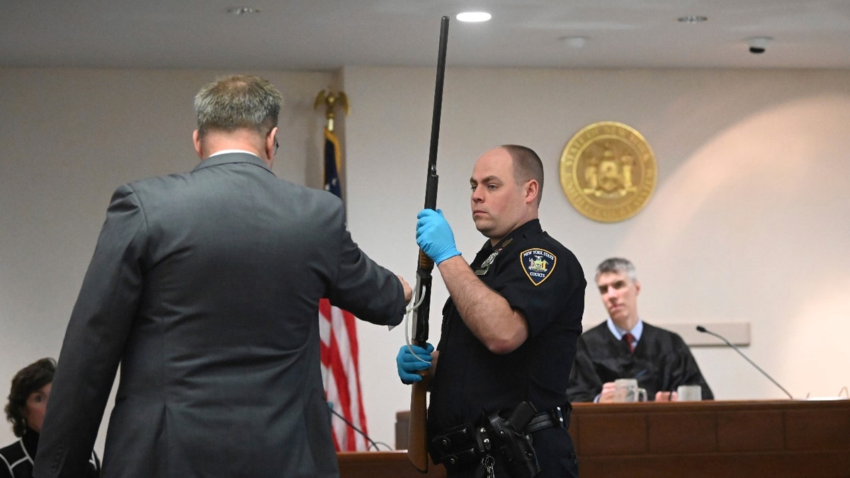 Washington County First Assistant District Attorney Christian P. Morris, left, directs a NYS Court Police officer to hold Kevin Monahan's shotgun during summations in Monahan's murder trial before County Judge Adam Michelini, right, Tuesday, Jan. 23, 2024, at Washington County Courthouse in Fort Edward, N.Y.