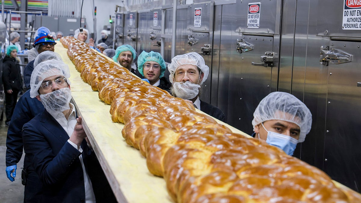 men holding giant loaf of bread