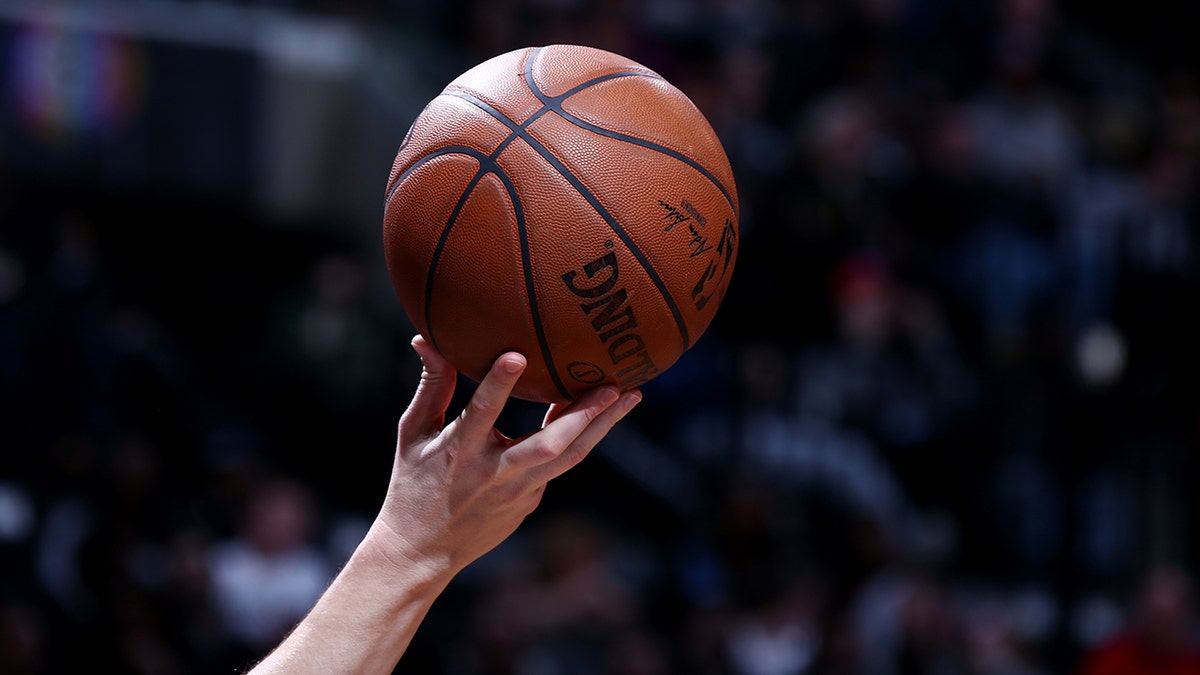 Referee lifts ball for tip-off at basketball game