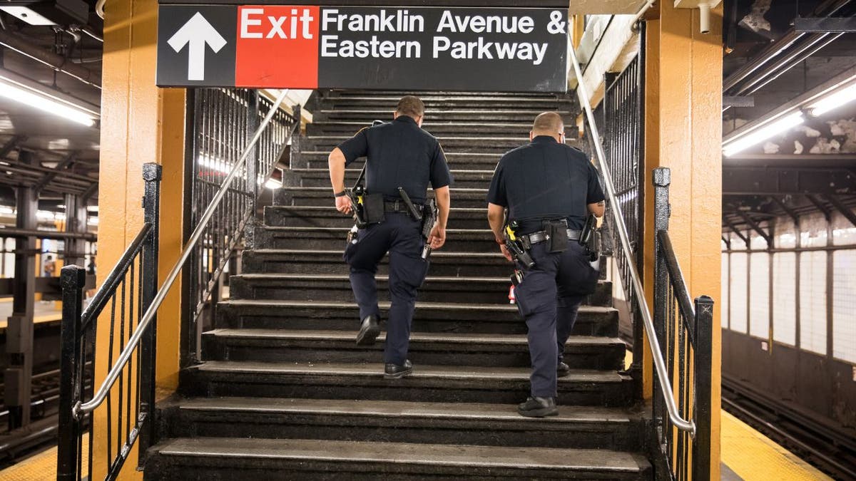 NYPD officers walk up stairs inside the Franklin Avenue subway station