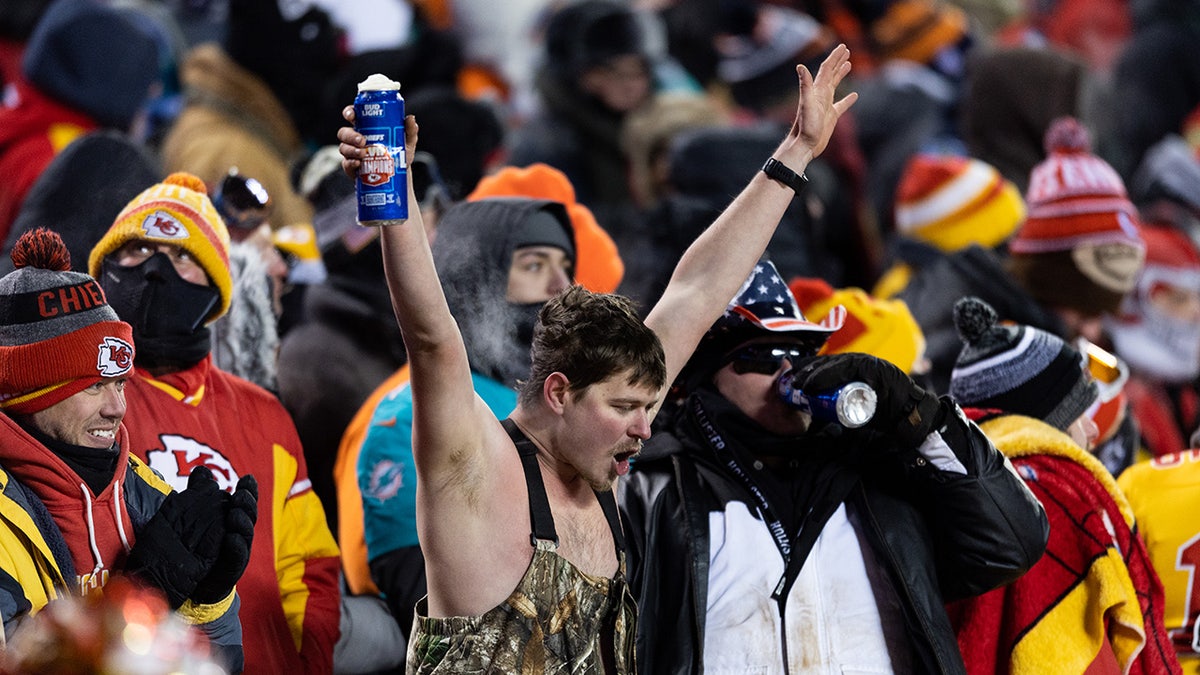 Chiefs fan in overalls raises hands in stands