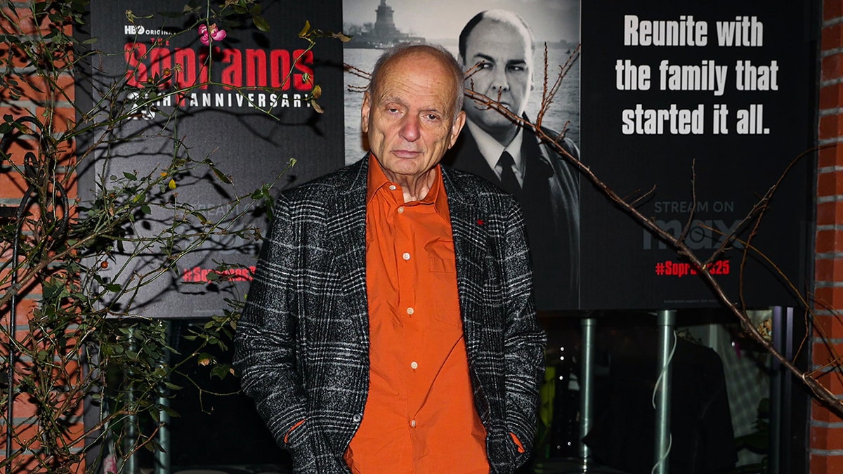 David Chase posing in front of Sopranos poster