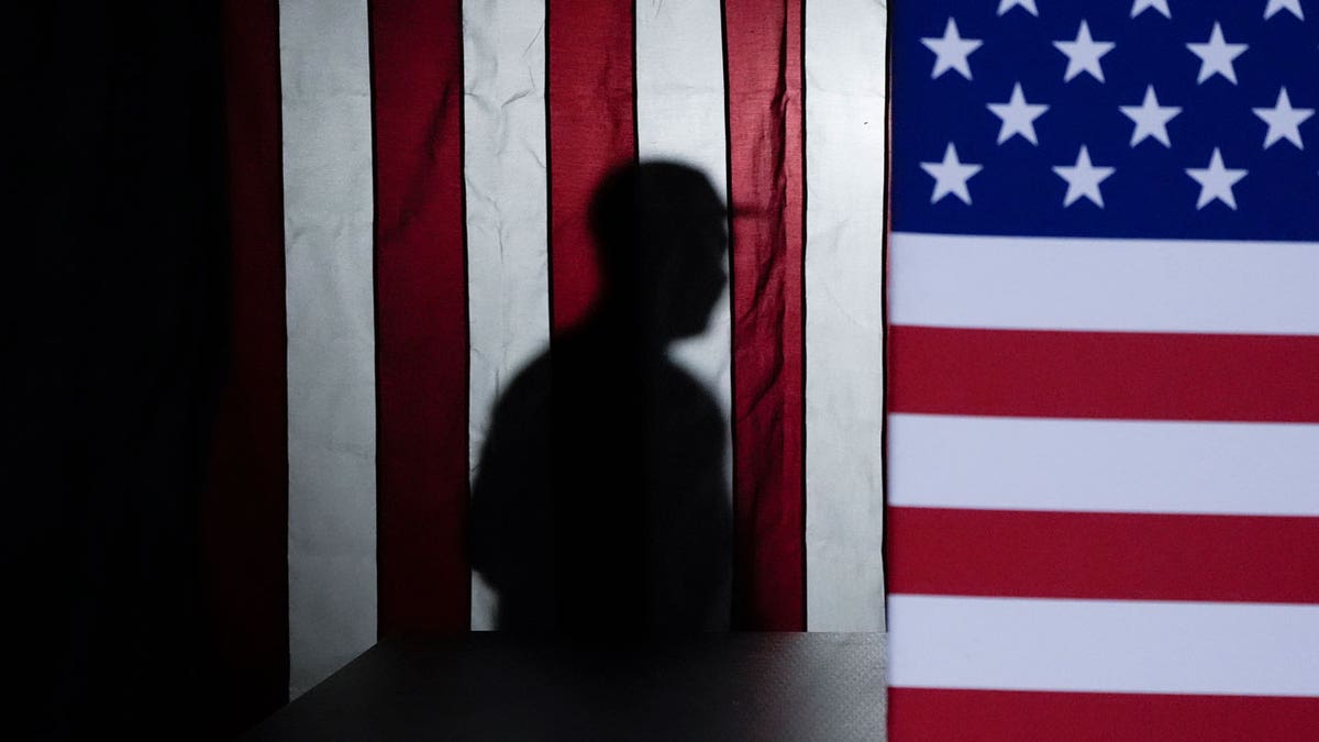 The silhouette of a person behind the American flag