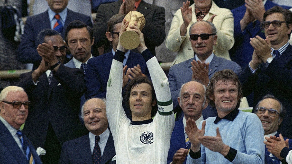 Franz Beckenbauer holds the trophy