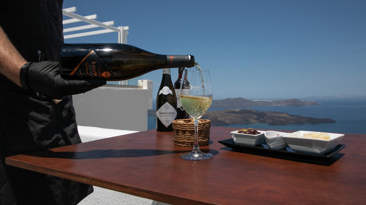 A waiter serves a glass of Assyrtiko wine on Santorini island in Greece