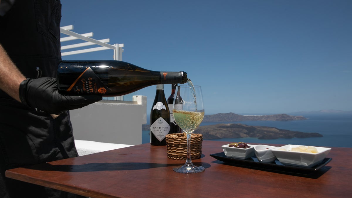 A waiter serves a glass of Assyrtiko wine on Santorini island in Greece