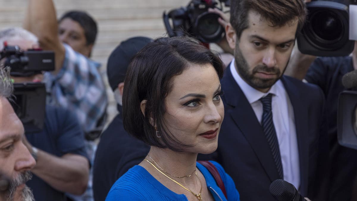 Sarah Ransome in blue dress with short hairspeaks to reporters outside court