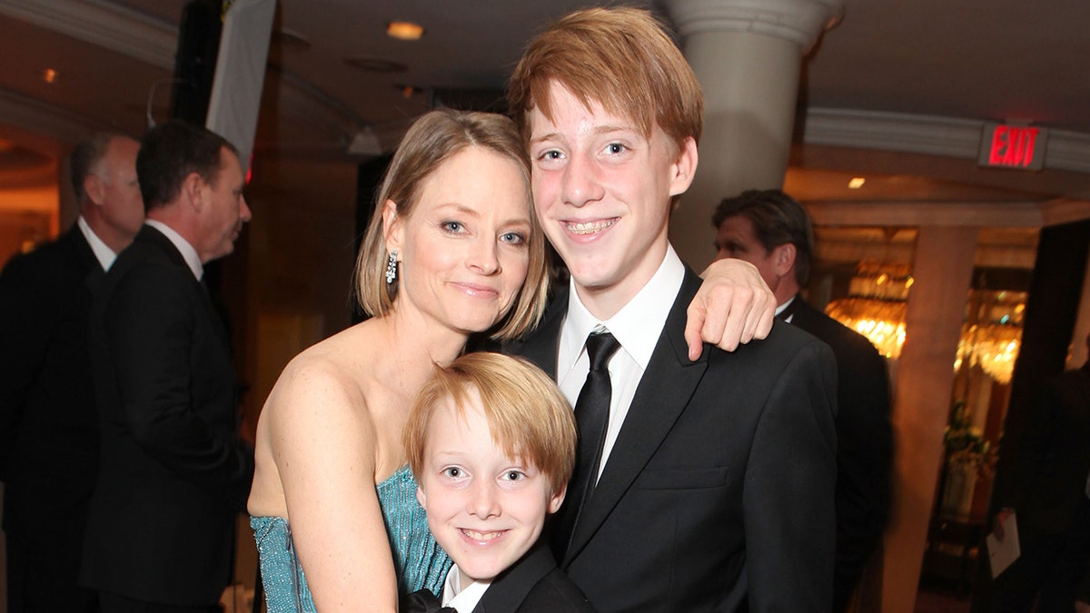 Jodie Foster in a teal dress hugs her sons Christopher and Charlie at the Golden Globes