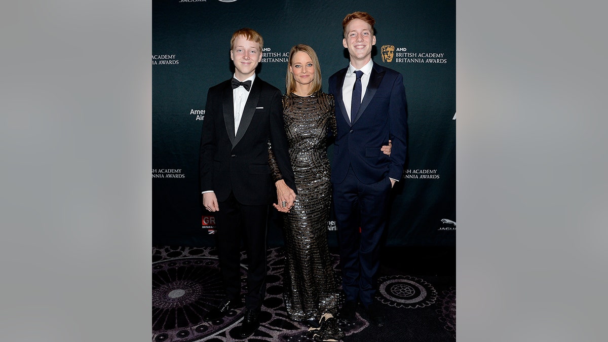 Jodie Foster em um vestido brilhante posa com seus dois filhos Charles e Christopher