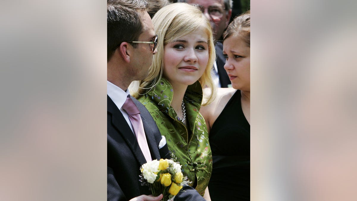 Elizabeth Smart in a green dress looking at a man in glasses