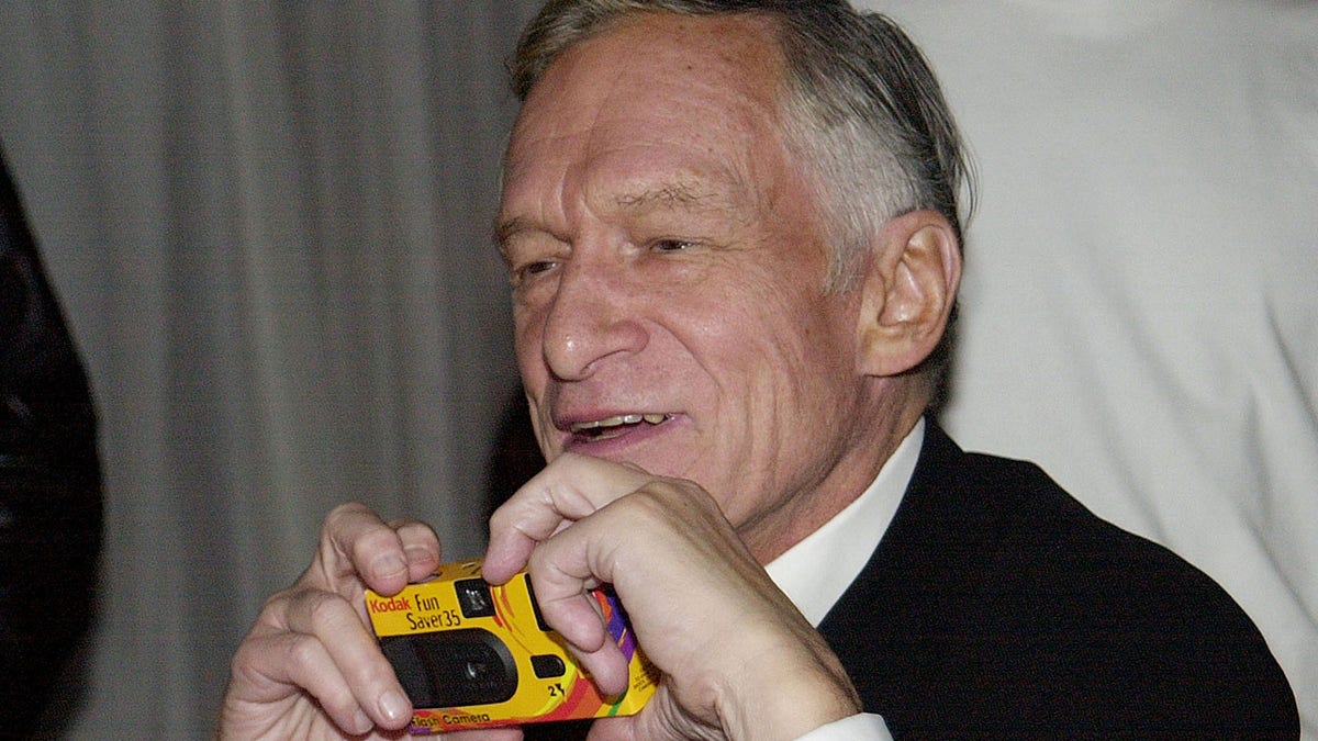 Hugh Hefner holding a disposible camera