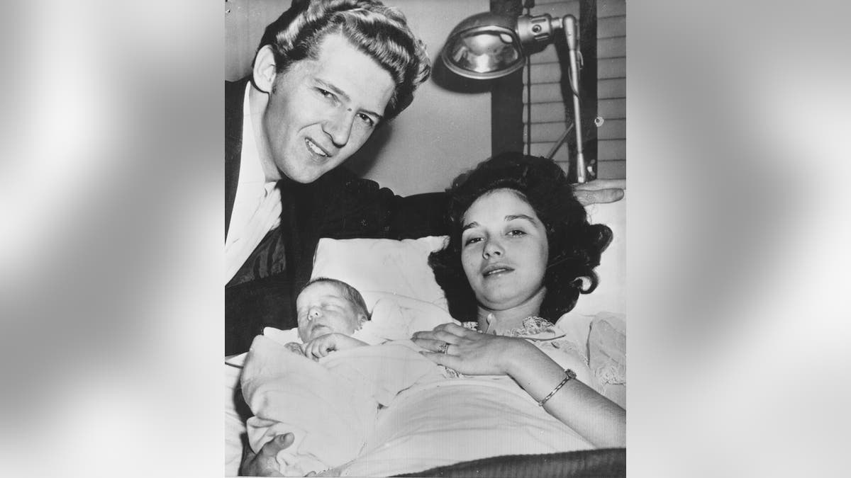 Myra Williams in bed holding her baby son as Jerry Lee Lewis looks on