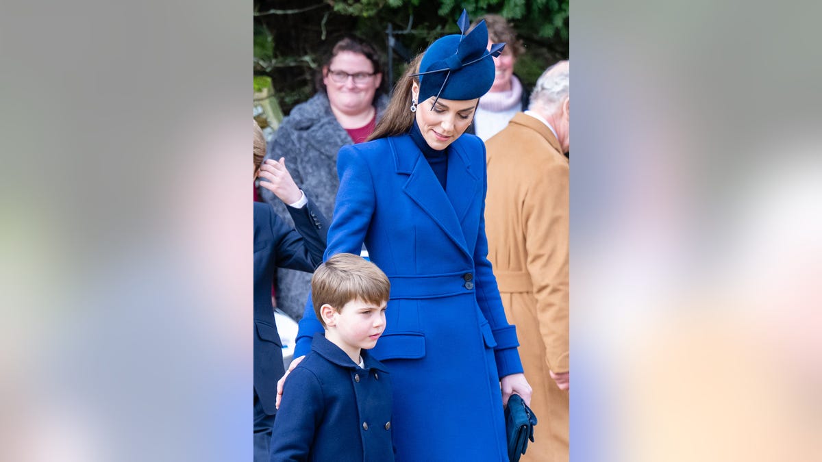 Kate Middleton in a bright blue coat dress looking at her son Prince Louis