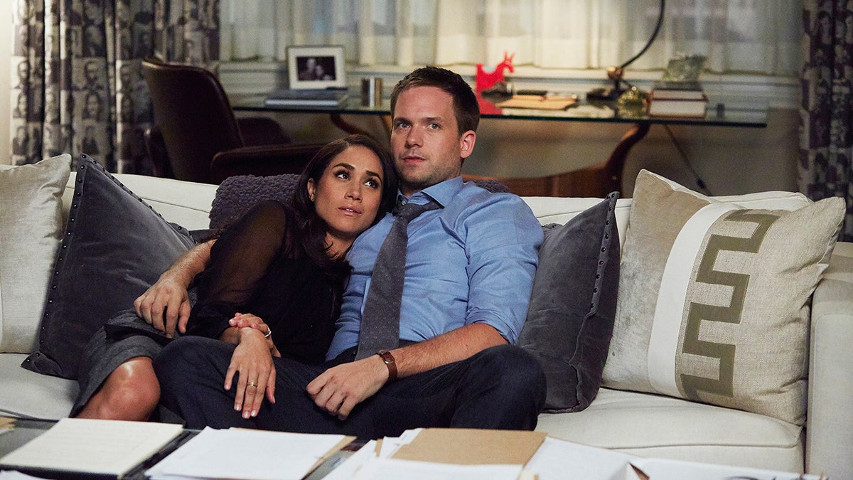 Meghan Markle laying on Patrick J. Adams in a scene from Suits