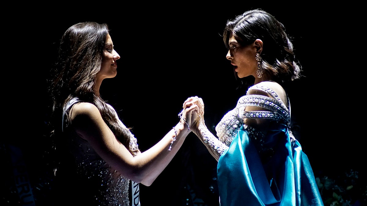 Two Miss Universe contestants holding hands as they wait to hear who is the winner