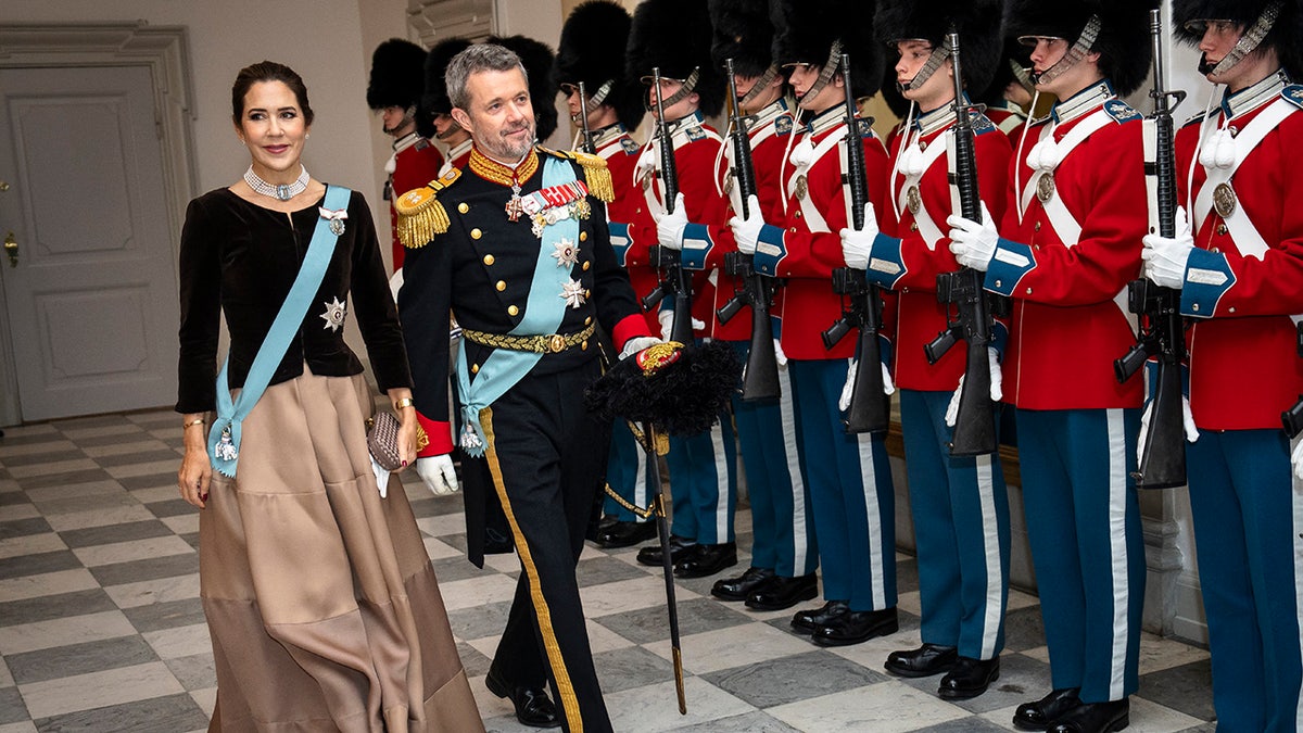 O príncipe herdeiro Frederik e a princesa herdeira Mary caminhando perto de uma fila de guardas militares
