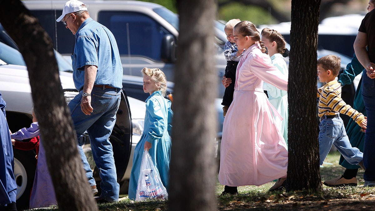 Women and children being escorted out of a ranch