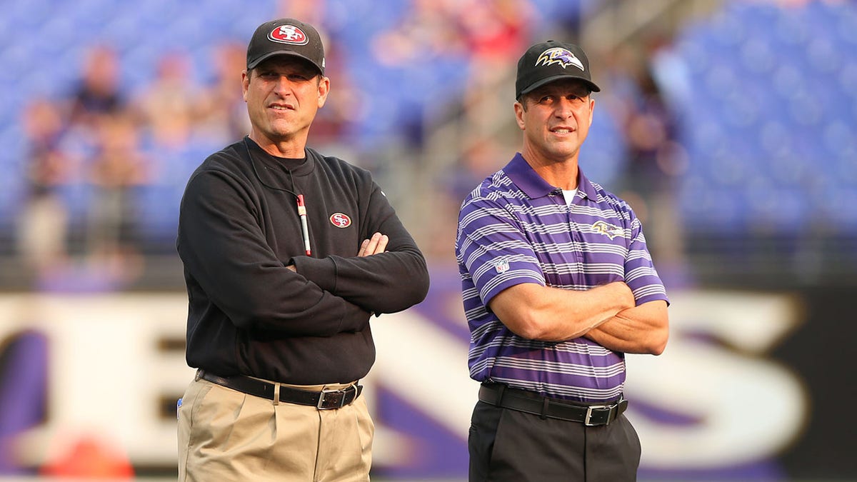 Jim Harbaugh stands next to his brother John Harbaugh