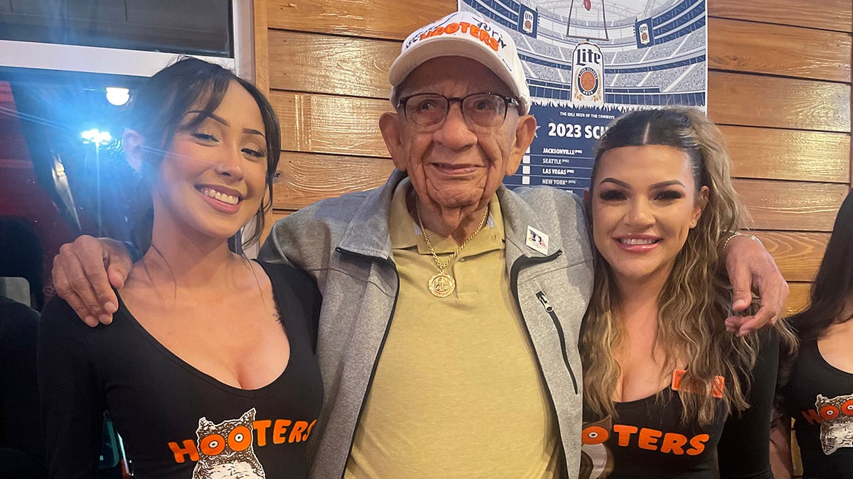 elderly man with two Hooters waitresses