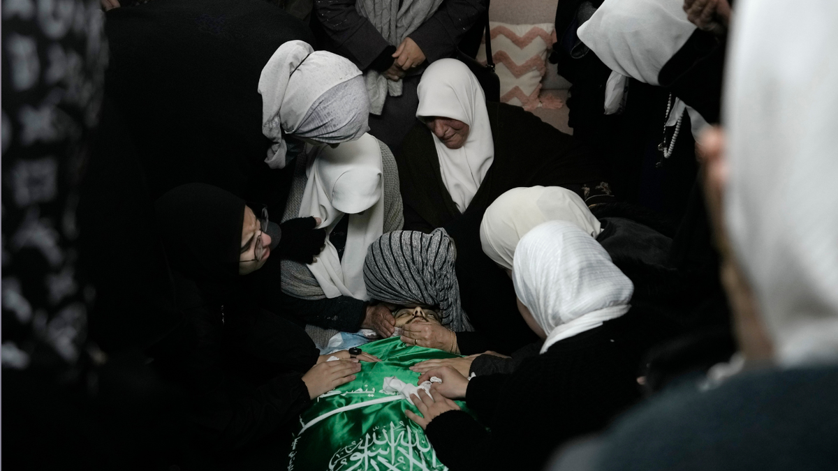 Palestinian women gather around the body of Muhammad Jalamneh, draped in the Hamas militant group flag