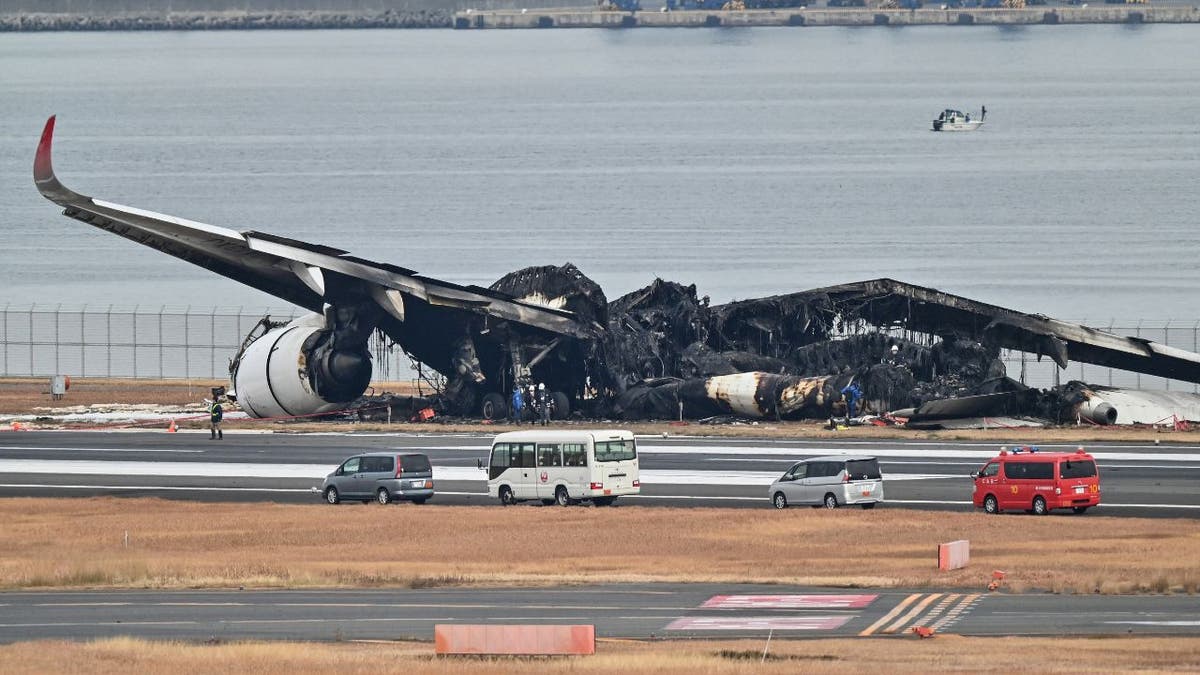 Officials look at the burnt wreckage of a Japan Airlines (JAL) passenger plane on the tarmac at Tokyo International Airport at Haneda in Tokyo on January 3, 2024